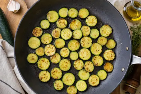 Rondes tranches de courgette au four, dorées et légèrement grillées dans une poêle, prêtes à être dégustées.