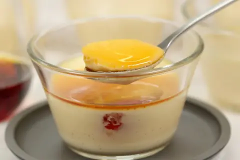 Cuillère de crème caramel onctueuse, nappée de sauce dorée, dans un verre. Un délice à savourer.