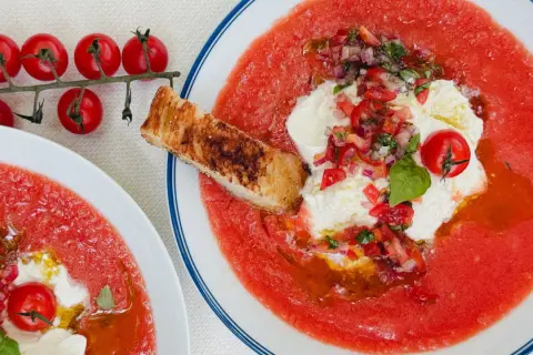 Soupe à la tomate rafraîchissante avec burrata, tomates cerises, oignons rouges, basilic et croûton grillé. Un délice estival.