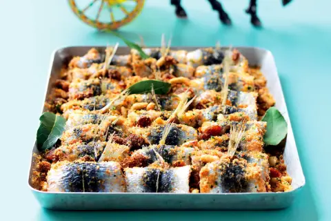 Sardes à beccafico, un plat sicilien appétissant, garni de chapelure, pignons et raisins secs, dans un plat de cuisson.