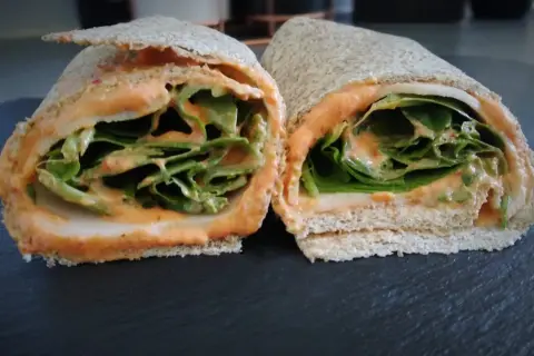 Deux moitiés d'un wrap jambon garni de feuilles de laitue croquantes et d'une sauce crémeuse.