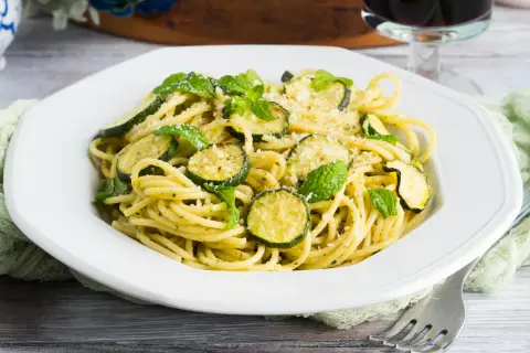 Spaghetti alla Nerano, un plat de pâtes crémeux aux courgettes et à la menthe fraîche, garni de parmesan râpé.