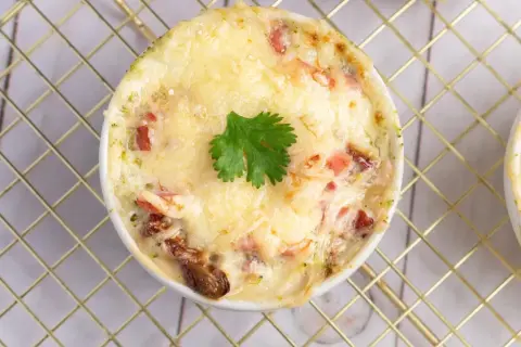Un gratin de brocolis crémeux et doré, garni d'une feuille de persil, prêt à être dégusté.
