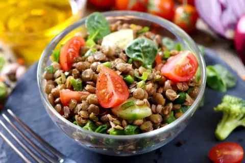 Salade de lentilles traditionnelle, fraîche et colorée, garnie de tomates cerises, concombre et oignons verts. Un délice sain.