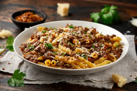 Un plat généreux de pâtes penne, nappées d'une sauce riche et savoureuse, rappelant la tradition de la pasta alla genovese. Saupoudré de parmesan et garni de persil frais.