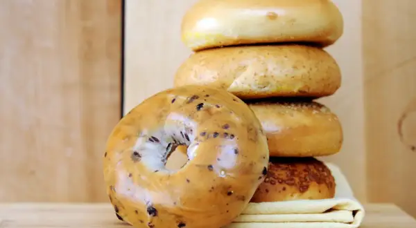 Pile de bagels, dont un aux myrtilles en premier plan. Parfait pour une recette bagel maison.