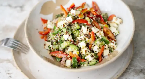 Salade quinoa colorée avec des dés de feta, concombre, poivrons rouges et herbes fraîches. Un plat sain et savoureux.