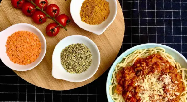 Spaghetti al pomodoro avec lentilles corail, tomates cerises, curcuma et anis étoilé. Un plat savoureux et coloré.