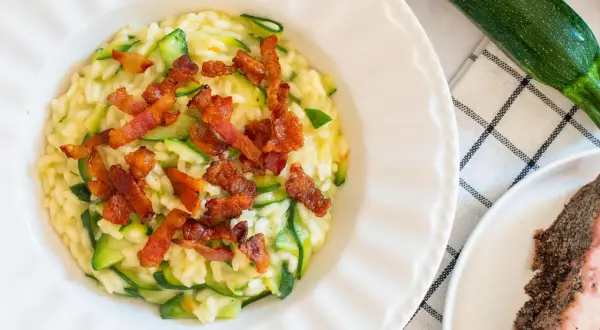 Risotto crémeux aux courgettes, garni de croustillantes tranches de guanciale. Un délice italien.