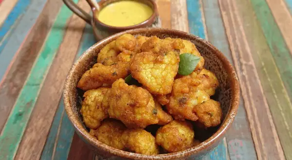 Beignets de choux-fleur italiens dorés et croustillants, servis dans un bol avec une sauce crémeuse.