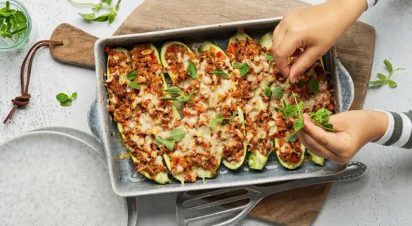 Courgettes farcies à la viande hachée, gratinées au fromage et garnies d'herbes fraîches. Une recette savoureuse prête à être dégustée.