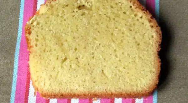 Une tranche de torta margherita, moelleuse et dorée, posée sur une serviette rayée rose et blanche.