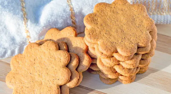 Délicieux biscuit sans beurre avec huile, en forme de fleur, empilés sur une planche en bois.