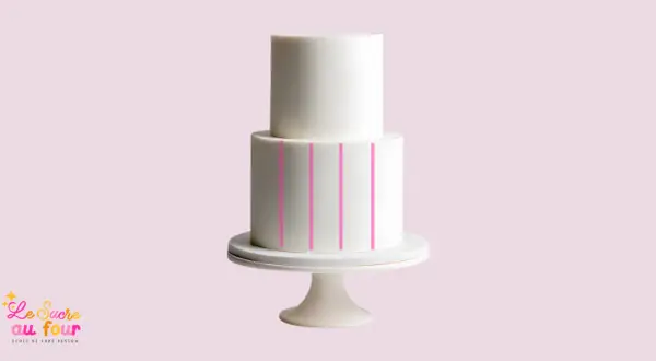 Un gâteau blanc à deux étages sur un présentoir, avec des lignes roses indiquant comment faire un gâteau de couche.