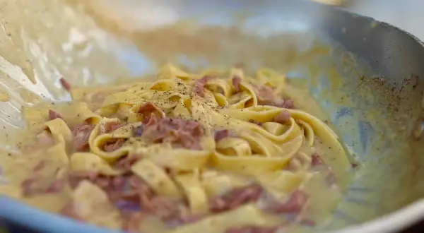 Fettuccine alla papalina crémeux et poivré, servi dans une poêle.
