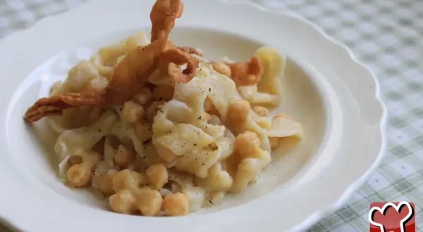 Un plat de ciceri e tria, pâtes fraîches et pois chiches, garni d'une feuille de pâte frite croustillante.
