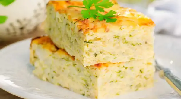 Deux parts de flan de courgettes facile, garnies de persil frais, sur une assiette blanche.