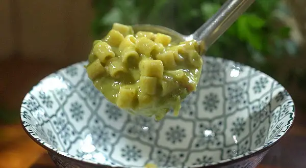 Une louche de pâtes ditalini dans une sauce crémeuse aux petits pois, parfaite pour une recette italienne simple et savoureuse.