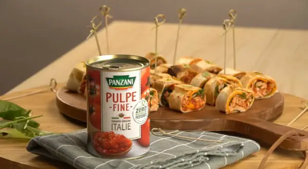 Délicieux wrap poulet garni de pulpe de tomate Panzani, présenté sur un plateau en bois avec des brochettes.