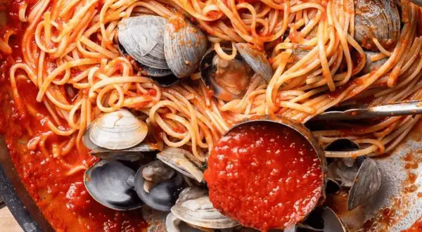 Spaghetti vongole tomate, un plat de pâtes aux palourdes et sauce tomate savoureuse, prêt à être dégusté.