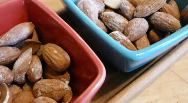 Deux bols, un rouge et un bleu, remplis d'amandes salées. Parfait pour un apéritif !