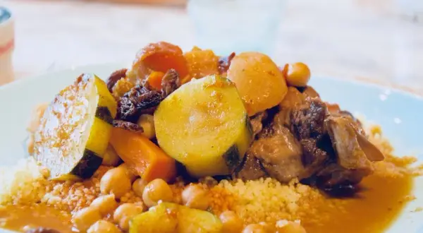 Un plat généreux de couscous algérien, garni de légumes tendres, de pois chiches et de viande savoureuse, baignant dans une sauce parfumée.