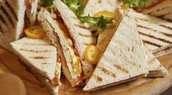 Tramezzini recette : des sandwichs triangulaires grillés, garnis de légumes frais et de garnitures savoureuses, prêts à être dégustés.