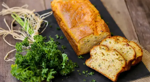 Un délicieux cake au thon, doré et moelleux, coupé en tranches. Accompagné de persil frais, parfait pour une recette facile.