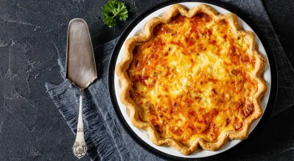 Une délicieuse tarte au fromage dorée, prête à être servie avec une touche de persil.