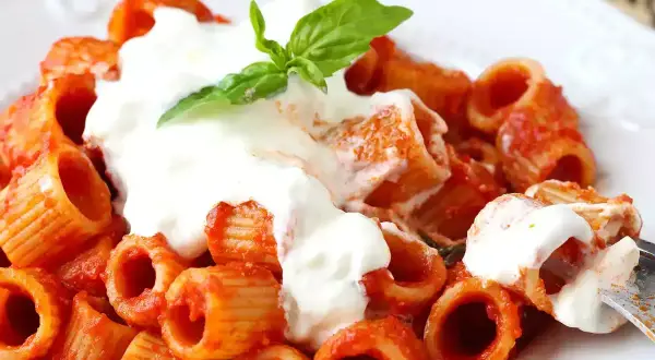 Pâtes rigatoni en sauce tomate, généreusement nappées de stracciatella crémeuse et garnies d'une feuille de basilic frais. Un délice !