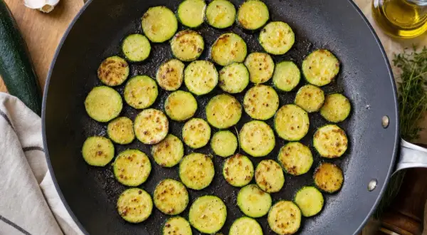 Rondes tranches de courgette au four, dorées et légèrement grillées dans une poêle, prêtes à être dégustées.