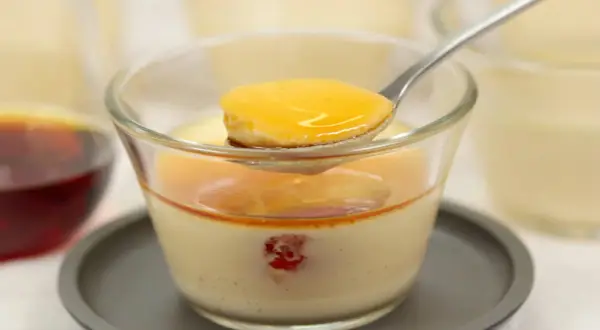 Cuillère de crème caramel onctueuse, nappée de sauce dorée, dans un verre. Un délice à savourer.