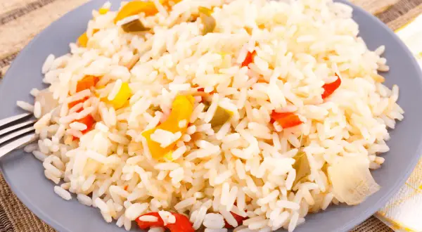 Une assiette de riz créole coloré avec des morceaux de poivrons rouges et jaunes.