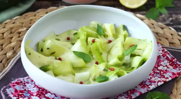 Salade fraîche de courgettes crues marinées au vinaigre, parsemée de baies roses et de menthe.