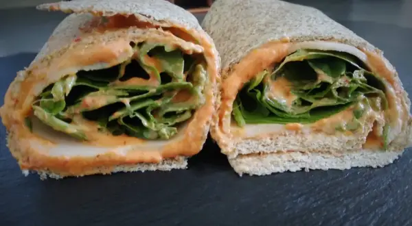 Deux moitiés d'un wrap jambon garni de feuilles de laitue croquantes et d'une sauce crémeuse.