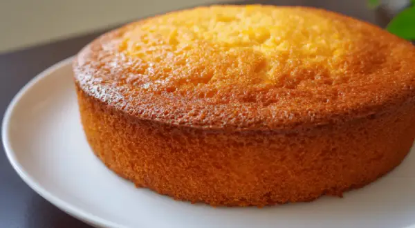 Un délicieux gâteau mandarine, doré et moelleux, posé sur une assiette blanche. Parfait pour le goûter.