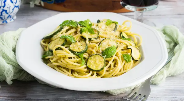 Spaghetti alla Nerano, un plat de pâtes crémeux aux courgettes et à la menthe fraîche, garni de parmesan râpé.