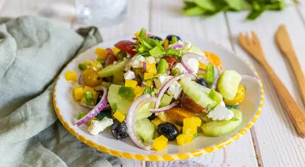 Salade de petit épeautre à la grecque, colorée et fraîche, avec concombre, tomates, poivrons, olives, oignons rouges et feta.