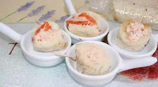Petites bouchées de pain garnies de rillettes de saumon, présentées dans des cuillères de service.
