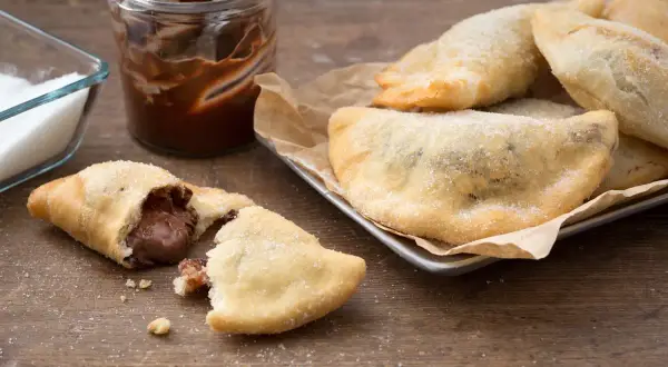 Des panzerotti nutella dorés et saupoudrés de sucre, un délice gourmand prêt à être dégusté.