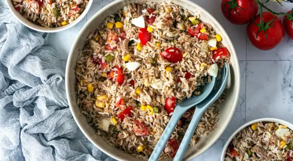 Une généreuse salade de riz italienne, garnie de thon, tomates, maïs et œufs durs, prête à être dégustée.
