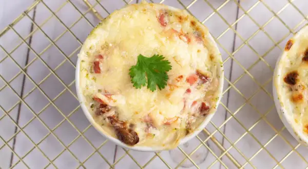 Un gratin de brocolis crémeux et doré, garni d'une feuille de persil, prêt à être dégusté.
