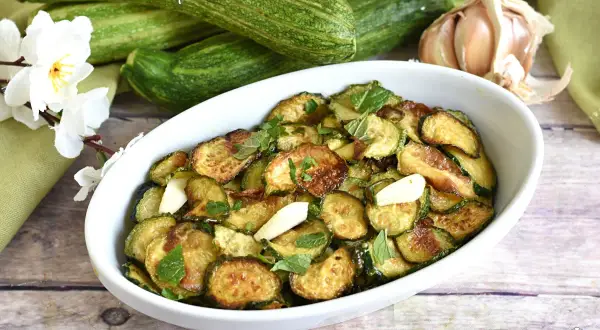 Zucchine alla scapece, un plat savoureux de courgettes frites, ail et menthe, servi dans un plat blanc.