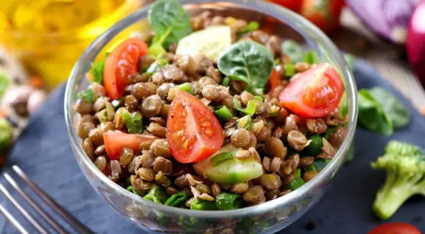 Salade de lentilles traditionnelle, fraîche et colorée, garnie de tomates cerises, concombre et oignons verts. Un délice sain.