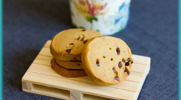 Pile de biscuits au café parsemés de pépites de chocolat, sur une petite palette en bois.
