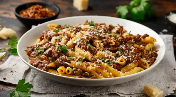 Un plat généreux de pâtes penne, nappées d'une sauce riche et savoureuse, rappelant la tradition de la pasta alla genovese. Saupoudré de parmesan et garni de persil frais.