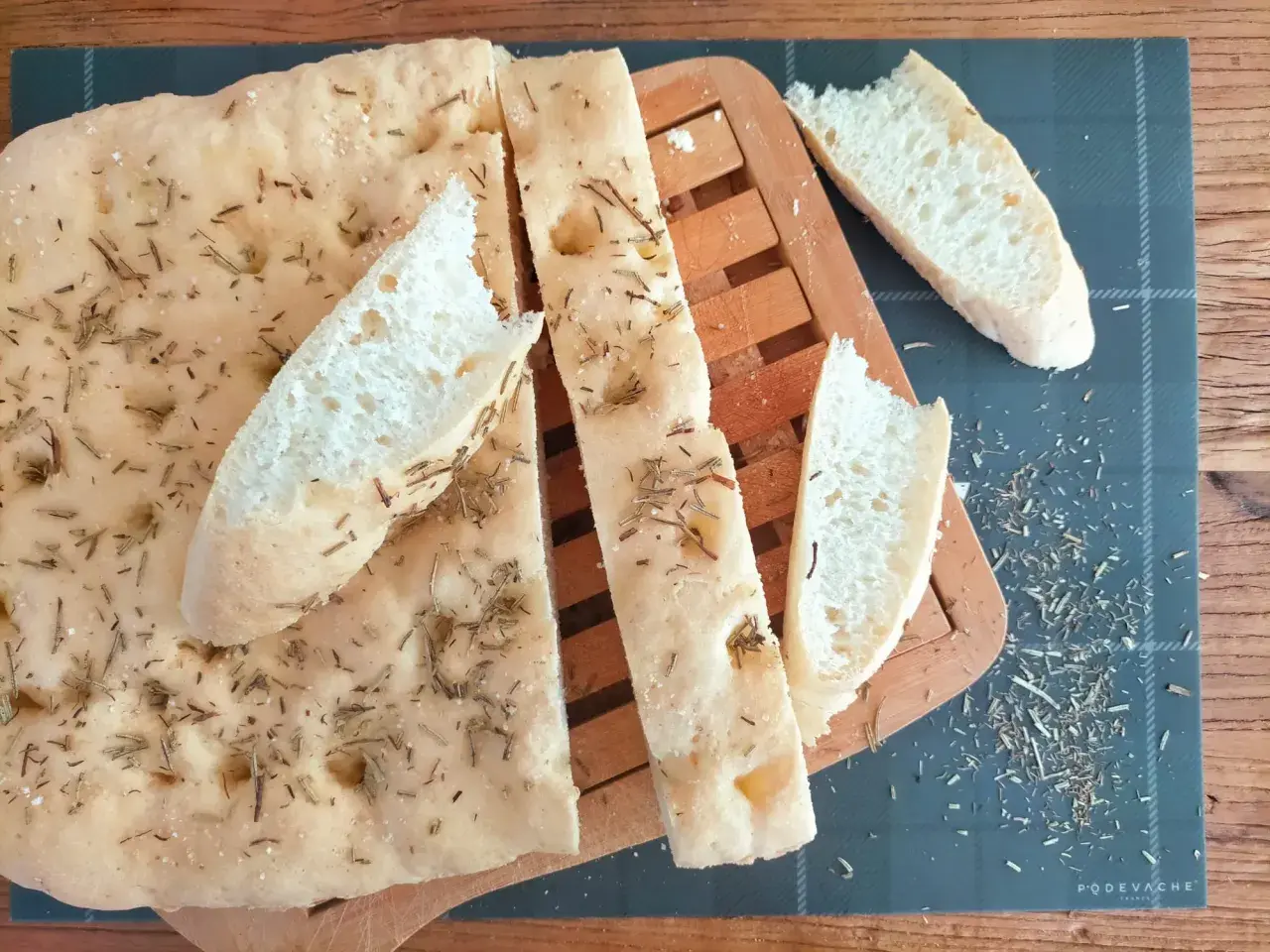 Délicieuse focaccia sans gluten, parsemée de romarin et de sel, coupée en tranches sur une planche en bois.