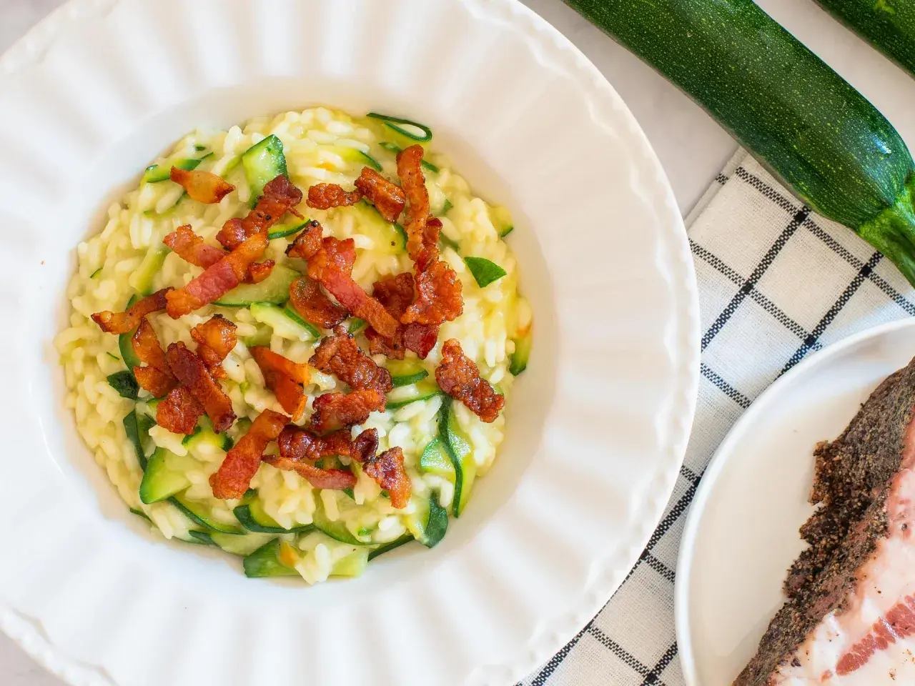 Risotto crémeux aux courgettes, garni de croustillantes tranches de guanciale. Un délice italien.