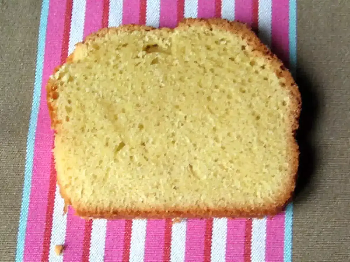 Une tranche de torta margherita, moelleuse et dorée, posée sur une serviette rayée rose et blanche.