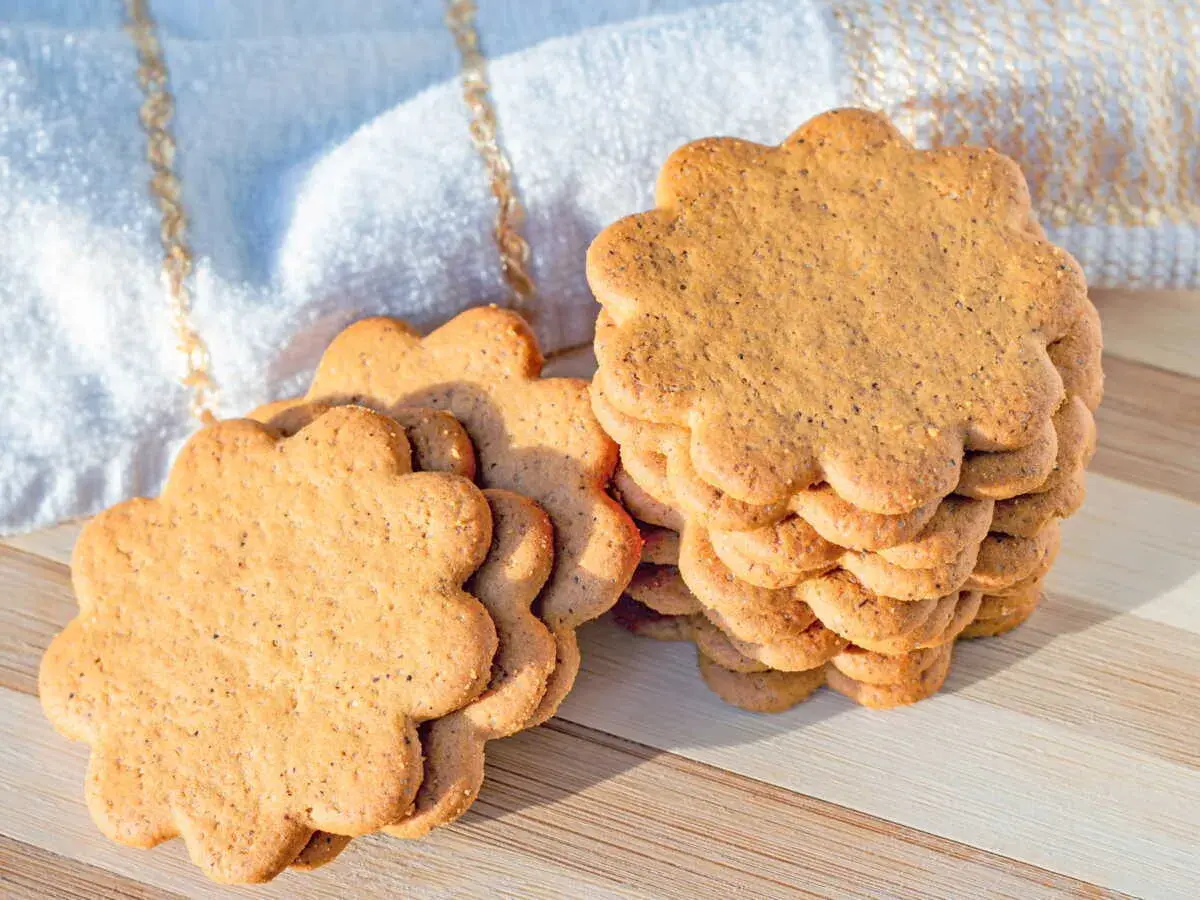 Délicieux biscuit sans beurre avec huile, en forme de fleur, empilés sur une planche en bois.